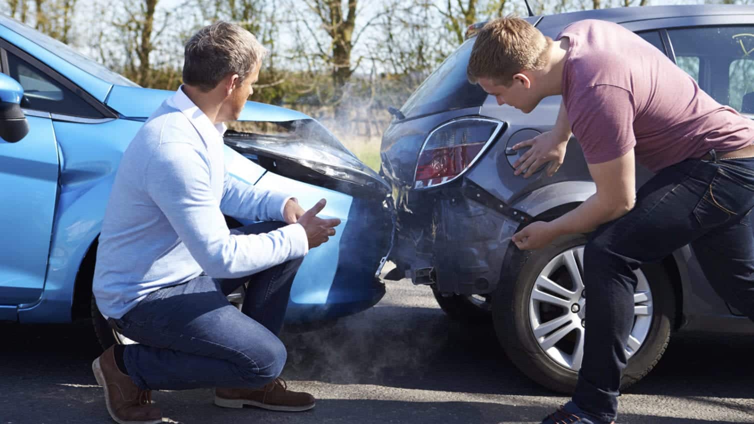 Two men inspecting damage after a rear-end collision between a blue car and a gray car on a road, with visible smoke from the impact.